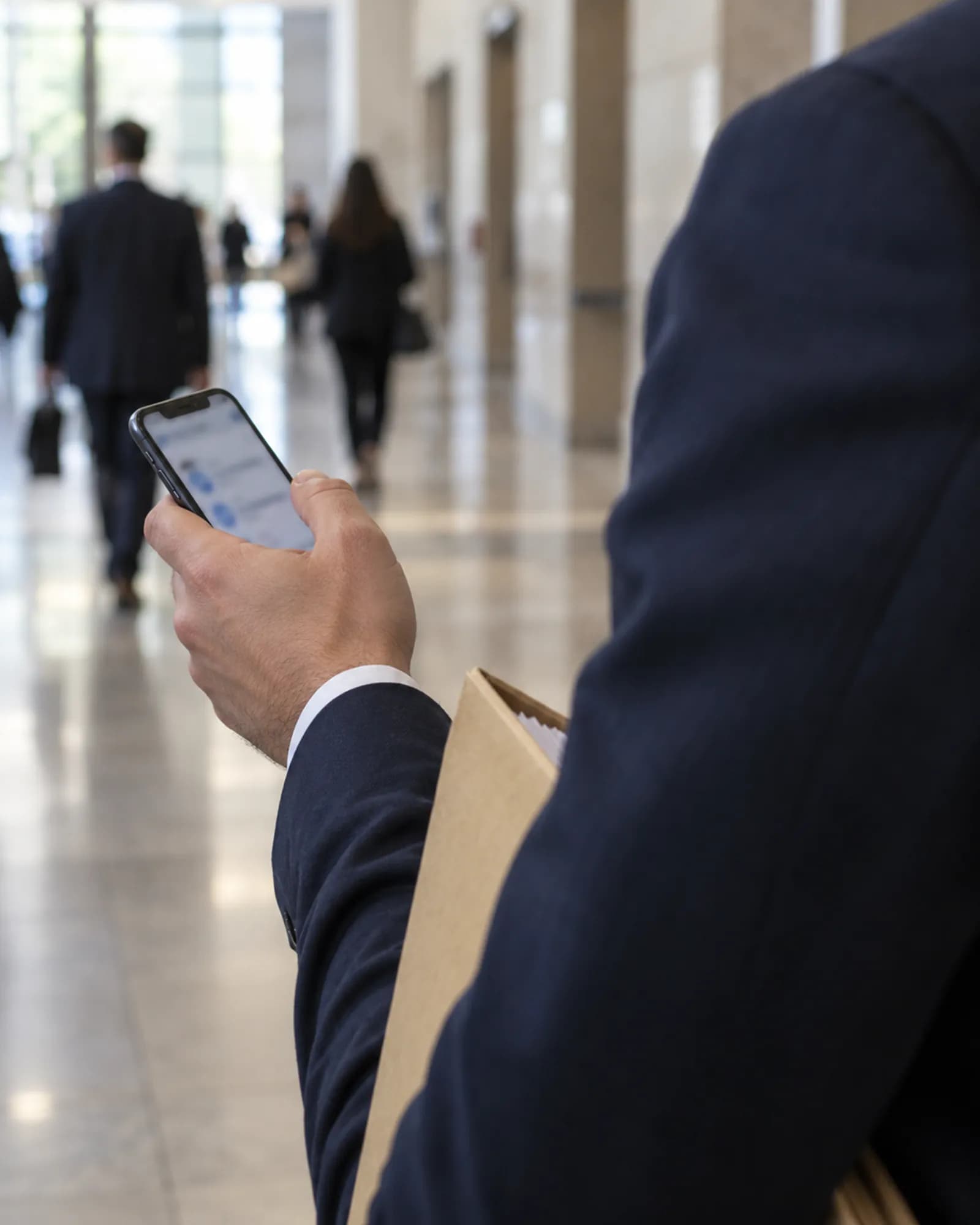 Adliye koridorunda telefonundan dava ajandasına bakan avukat