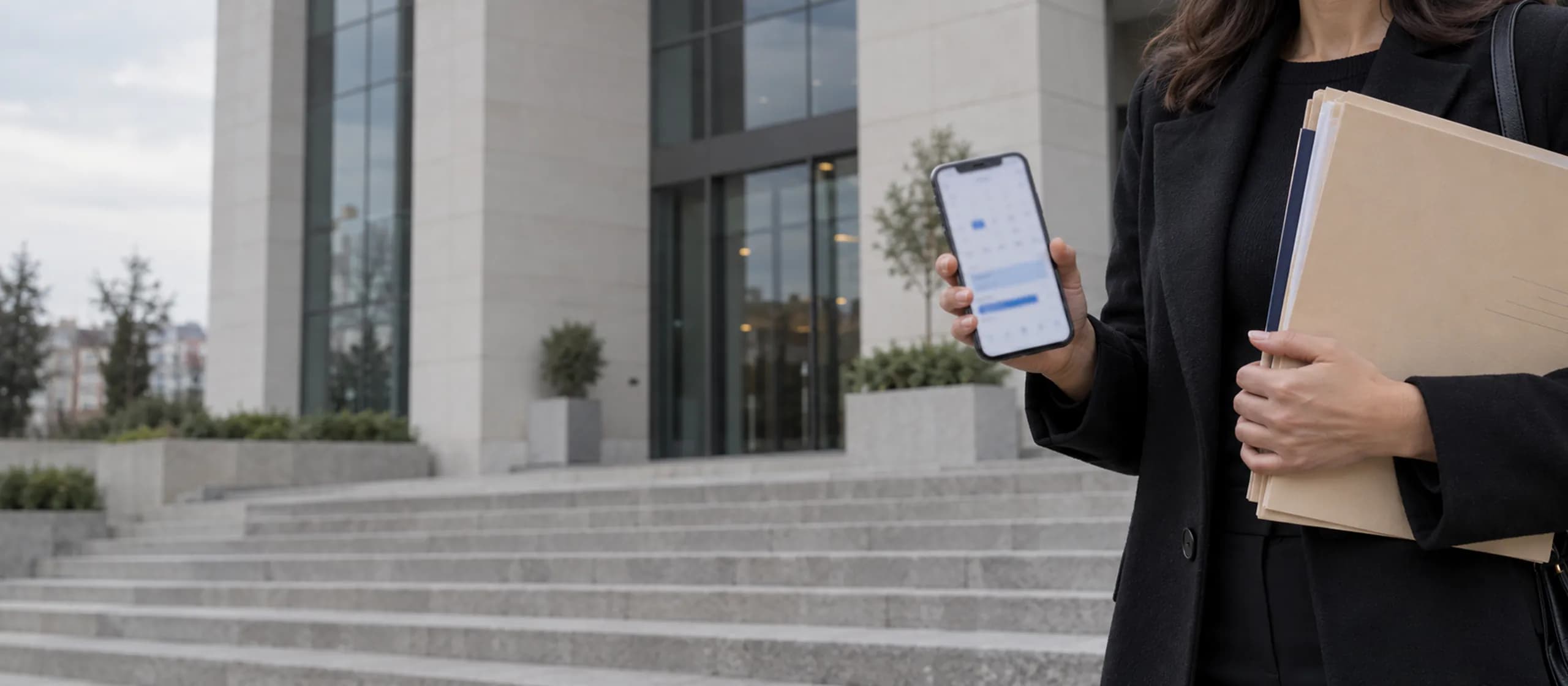 Büro yanınızda Adliye merdiveninde elinde telefon ve dava dosyasıyla duran avukat